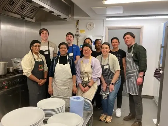 A group of volunteers posing for a photo in a kitchen