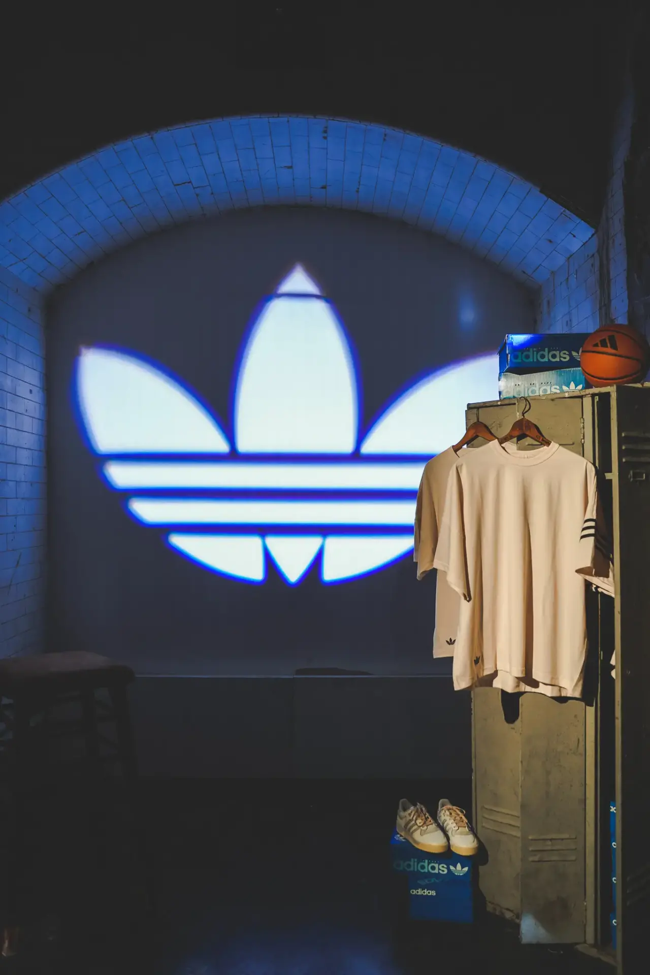 adidas clothing in a staged locker-room with a big logo projected on the back wall